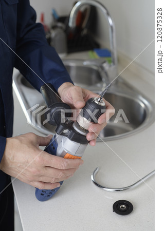 man puts a drill bit in a drill before to drill a hole man puts a drill bit in a drill before to drill a hole 120875328