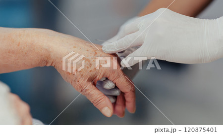 Close up of nurse administrating medication throught IV. Old woman with serious health issues. IV, intravenous therapy for elderly patient. 120875401