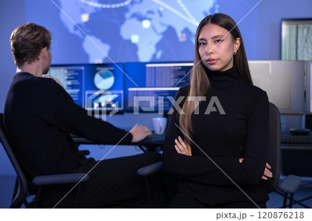 Serious Female Cybersecurity Analyst in large Cyber Security Operation Center SOC handling Threats 120876218