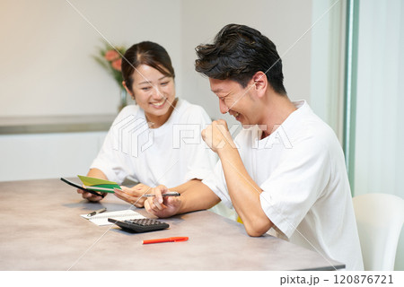 銀行口座の通帳を見る男女 120876721