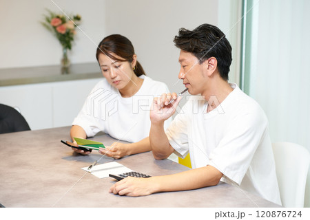 銀行口座の通帳を見る男女 120876724