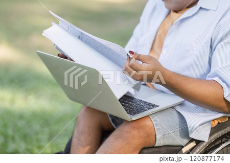 Young Disabled Businessman in Wheelchair Conducting Outdoor Work Inspection with Laptop and Documents in Hand Young Disabled Businessman in Wheelchair Conducting Outdoor Work Inspection with Laptop and Documents in Hand 120877174