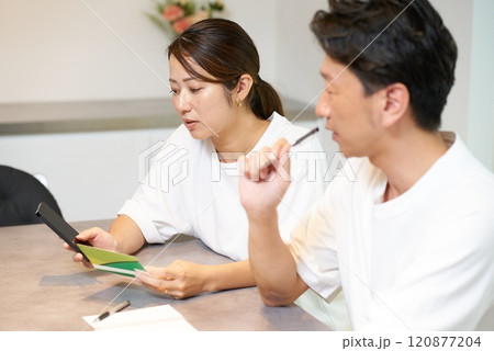 銀行口座の通帳とスマートフォンを見て考え込む男女 銀行口座の通帳とスマートフォンを見て考え込む男女 120877204