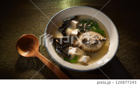 A bowl of soup with a spoon and a fish in it 120877243