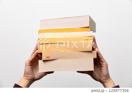 Stack of books in hand, Book Day, several books in hands on neutral white background. Home leisure. Self-isolation home, home schooling 120877308