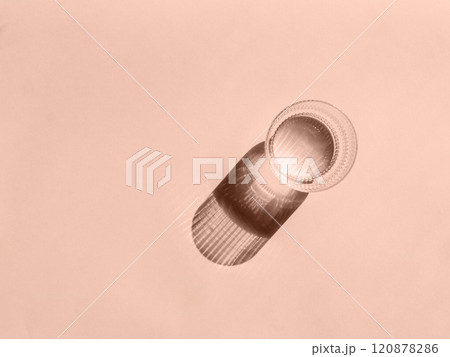 Glass of water and long shadow from sunlight on beige background 120878286
