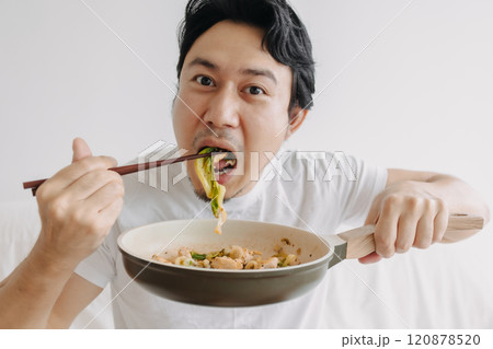 Close up of funny man eating his homemade lunch straight on the pan. 120878520