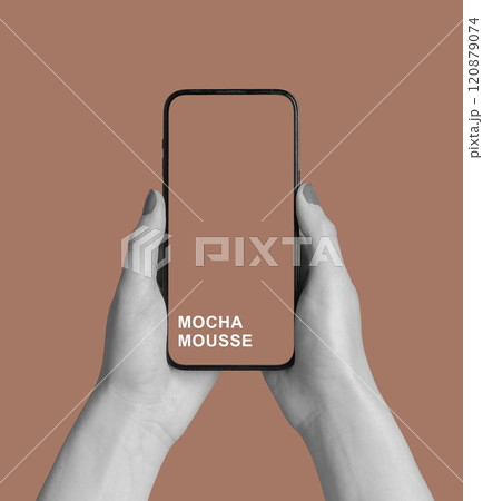 Mocha Mousse color on mobile phone screen in hands Mocha Mousse color on mobile phone screen in hands 120879074