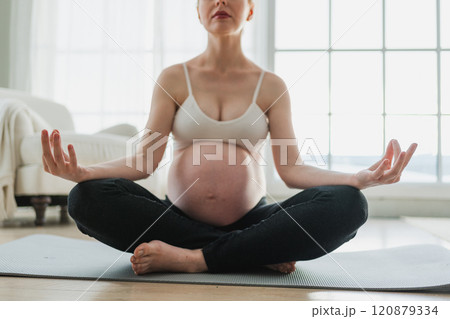 Pregnancy prenatal breathing. Pregnant woman with big belly sitting in lotus pose on yoga matt at home. Pregnant girl practicing yoga mindfulness meditation. Relaxation self care during pregnancy 120879334