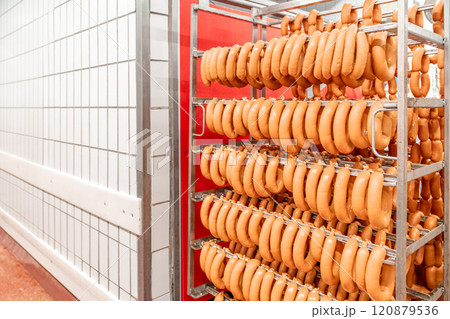 Sausage production line showing smoked sausages hanging in a modern food processing facility 120879536