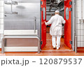 Butcher opening red door entering cold storage room in meat processing plant 120879537