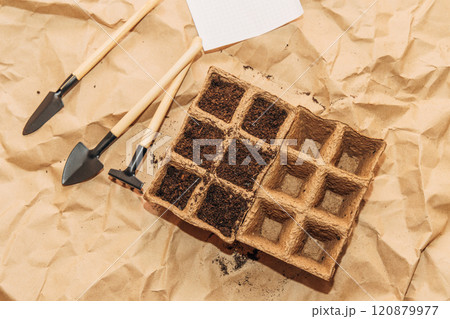 Kraft paper background, fertile soil and garden tools on top, top view. Planting seedlings in spring 120879977