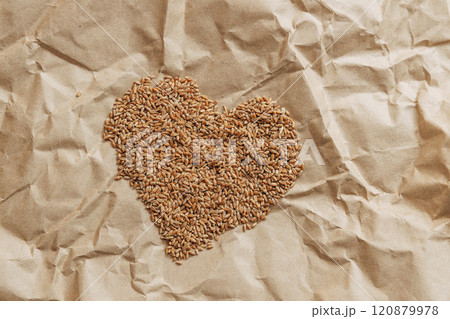 Golden wheat grains in the shape of a heart lie on a background of craft paper 120879978
