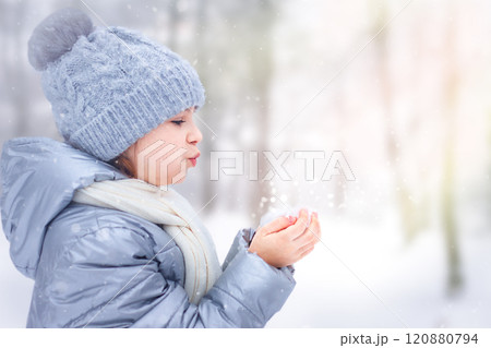 Little girl blowing snowflakes in a winter wonderland 120880794