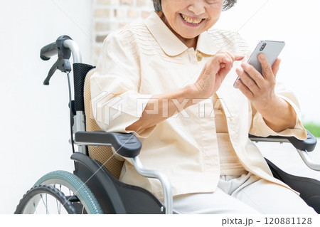 スマートフォンを操作する車椅子のシニア女性 120881128