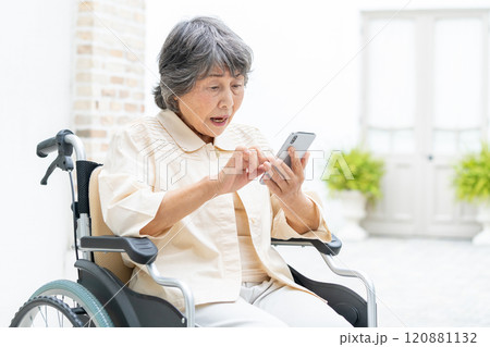 スマートフォンを操作する車椅子のシニア女性 120881132