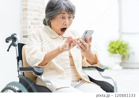 スマートフォンを操作する車椅子のシニア女性 スマートフォンを操作する車椅子のシニア女性 120881133