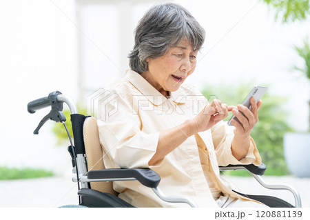 スマートフォンを操作する車椅子のシニア女性 スマートフォンを操作する車椅子のシニア女性 120881139