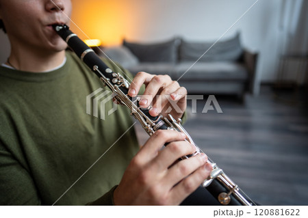 Clarinet player. Clarinetist hands playing flute woodwind music instrument at home, closeup view Clarinet player. Clarinetist hands playing flute woodwind music instrument at home, closeup view 120881622
