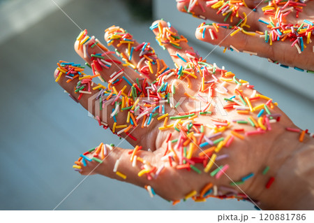 Hand covered in colorful baking sprinkles for donuts, cakes, sweet desserts and Easter cupcake. 120881786