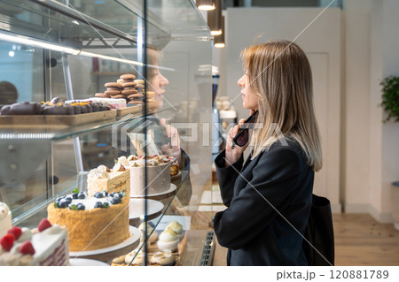 Contented stylish businesswoman interested choose sweet dessert while takes coffee break near office Contented stylish businesswoman interested choose sweet dessert while takes coffee break near office 120881789