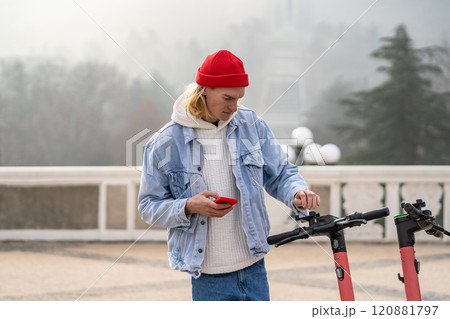 Puzzled guy standing at e-scooter parking, thinking how to pay for vehicles rent using application 120881797