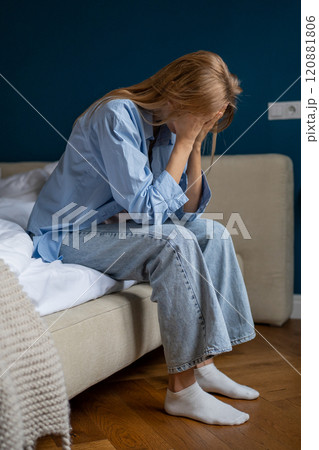 Young unhappy woman sitting on bed at home suffering from headache Young unhappy woman sitting on bed at home suffering from headache 120881806