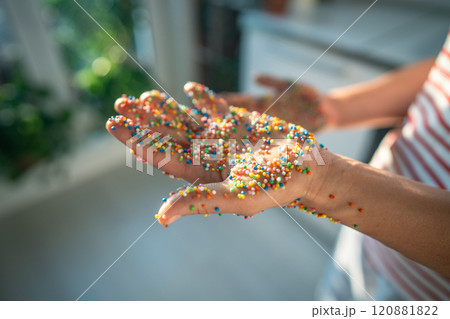 Hand covered in colorful baking sprinkles for donuts, cakes, sweet desserts and Easter cupcake. 120881822
