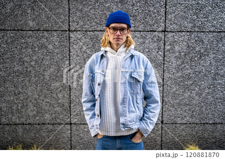 Blond long hair guy, scandinavian androgynous appearance in glasses standing on street. Blond long hair guy, scandinavian androgynous appearance in glasses standing on street. 120881870