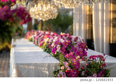 Long table decorated with fresh flowers. Interior of restaurant with flowering decorative plants. 120881933