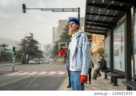 Young student guy waiting for bus. Man awaits at bus stop station. Public urban transport use Young student guy waiting for bus. Man awaits at bus stop station. Public urban transport use 120881935