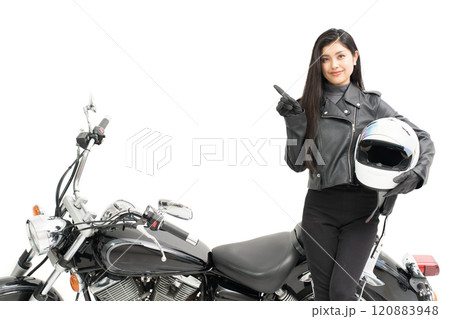 バイクの横に立って、ヘルメットを持って、指差しするバイク女子 120883948