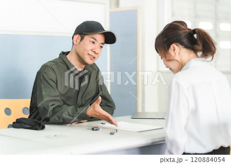 自動車整備工場の受付で説明・見積もり・提案をする整備士の男性と顧客の女性 120884054