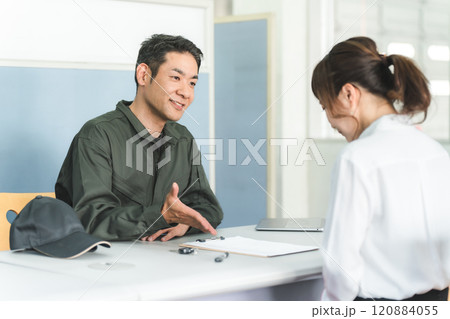 自動車整備工場の受付で説明・見積もり・提案をする整備士の男性と顧客の女性 120884055