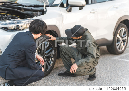 車の前で会話するスーツ姿のビジネスマンとつなぎ姿の自動車整備士の男性メカニック 車の前で会話するスーツ姿のビジネスマンとつなぎ姿の自動車整備士の男性メカニック 120884056