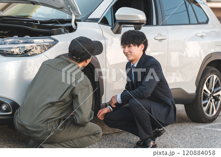 車の前で会話するスーツ姿のビジネスマンとつなぎ姿の自動車整備士の男性メカニック 120884058