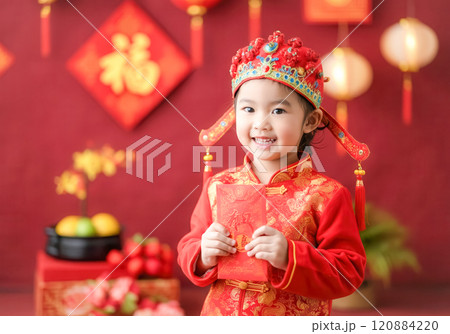 Joyful celebration, child in traditional attire holding red envelope for lunar new year 120884220