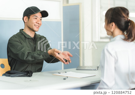 自動車整備工場の受付で接客をする整備士の男性と顧客の女性 自動車整備工場の受付で接客をする整備士の男性と顧客の女性 120884752
