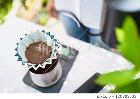Happy Asian beautiful woman making a specialty coffee in morning at her backyard garden, woman brewing a coffee by dripping or pouring over a hot water. 120885539