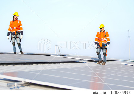 Professional electric engineers survey and inspect solar panels installation on the factory metal sheet roof top, electric engineer team inspecting and check solar cell system. 120885998