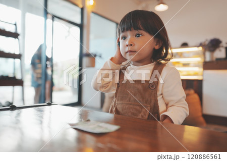 toddler girl talking with smartphone at cafe toddler girl talking with smartphone at cafe 120886561