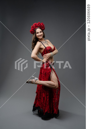 Elegant dancer in red costume with roses posing gracefully in studio Elegant dancer in red costume with roses posing gracefully in studio 120886689