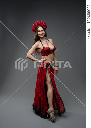 Elegant dancer in red attire with floral headpiece poses for a studio portrait Elegant dancer in red attire with floral headpiece poses for a studio portrait 120886691