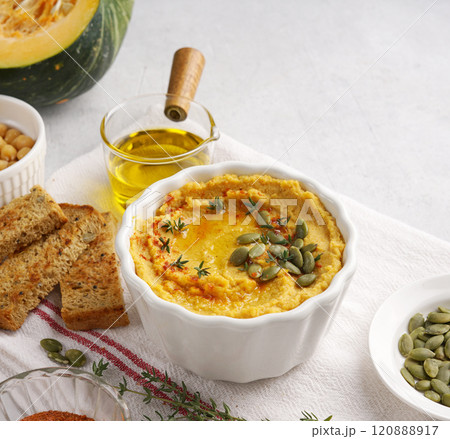 Homemade pumpkin chickpea hummus in a bowl on light background with ingredients. copy space 120888917