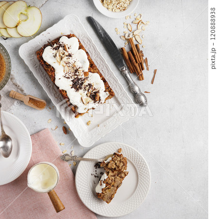 A piece of Spicy apple, nuts and oats loaf cake decorated with cream on a white plate, gluten free, top view, copy space A piece of Spicy apple, nuts and oats loaf cake decorated with cream on a white plate, gluten free, top view, copy space 120888938