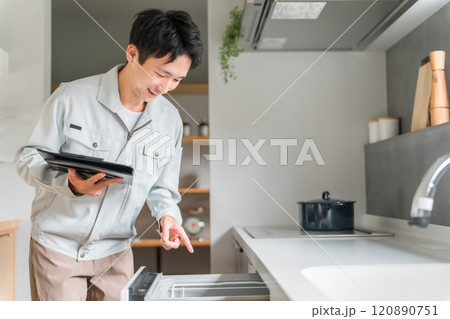 キッチンの食洗機・食器洗い乾燥機を診断・チェック・査定する作業服姿の男性ビジネスマン 120890751