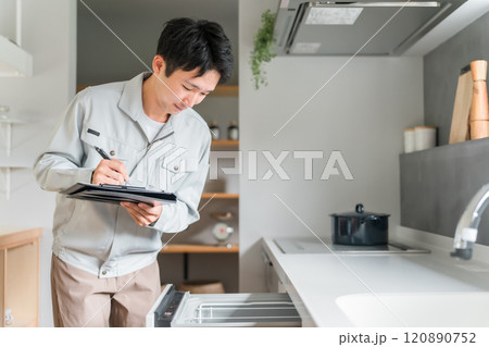 キッチンの食洗機・食器洗い乾燥機を診断・チェック・査定する作業服姿の男性ビジネスマン 120890752