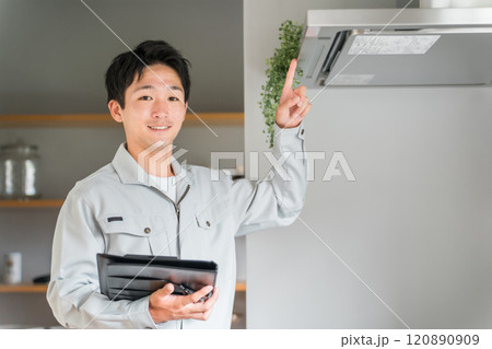 キッチンのレンジフード・換気扇を点検・チェックする作業着姿の男性ビジネスマン 120890909