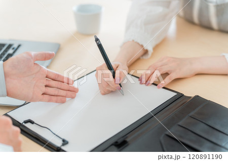 契約書・同意書にサインを求める作業着姿の営業マンの男性とサインをする主婦・女性の手元 契約書・同意書にサインを求める作業着姿の営業マンの男性とサインをする主婦・女性の手元 120891190