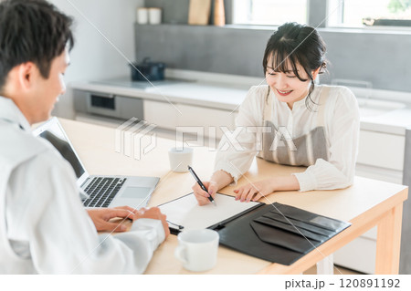 契約書・同意書にサインを求める作業着姿の営業マンの男性とサインをする主婦・女性 120891192